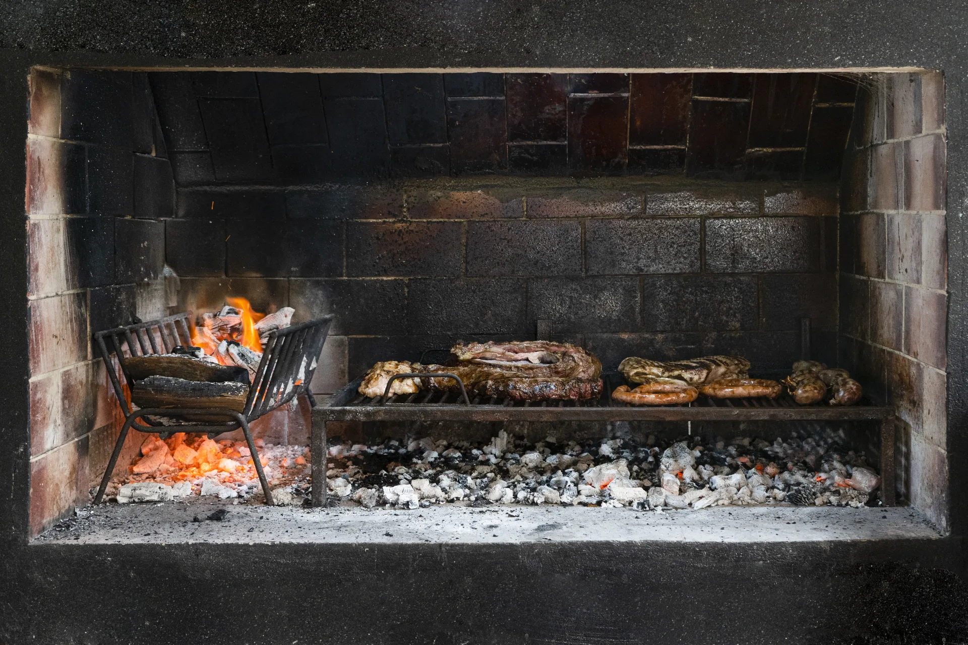 Barbecue argentino in muratura, carne sulla griglia sopra braci e fuoco