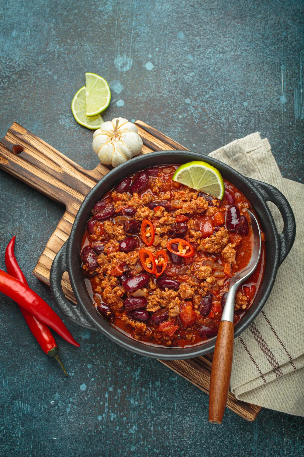 Chili con carne e fagioli in una casseruola, con peperoncini rossi e lime