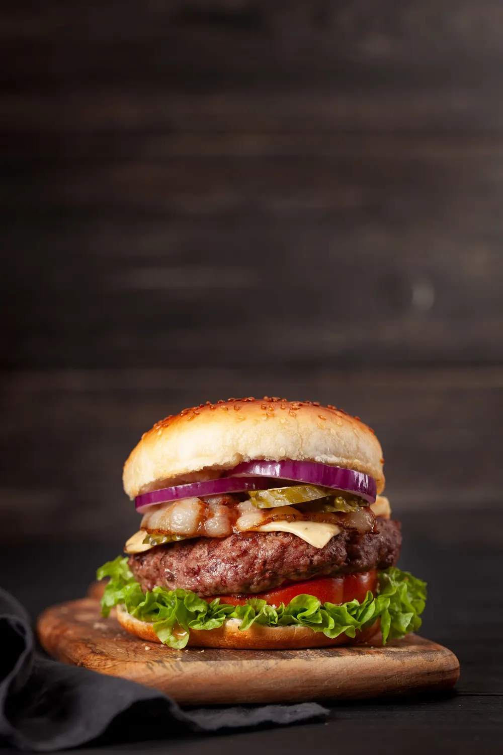 Hamburger con carne, formaggio, lattuga e cipolla rossa su un tagliere di legno