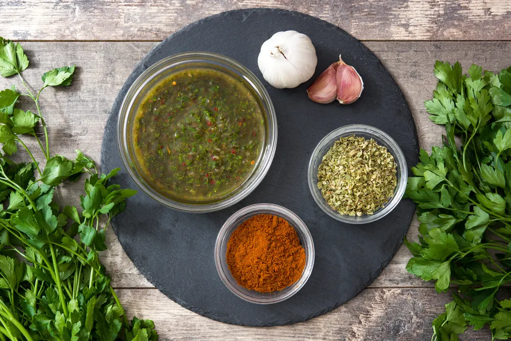 Ciotole di salsa alle erbe e spezie con aglio e prezzemolo su un piatto di ardesia